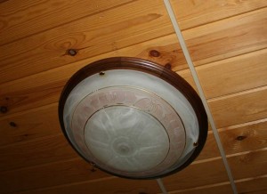 Round lamp with brown piping on the wood-paneled ceiling.