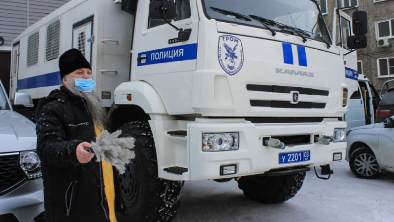 Russian Priest Blesses Police Van in Siberia