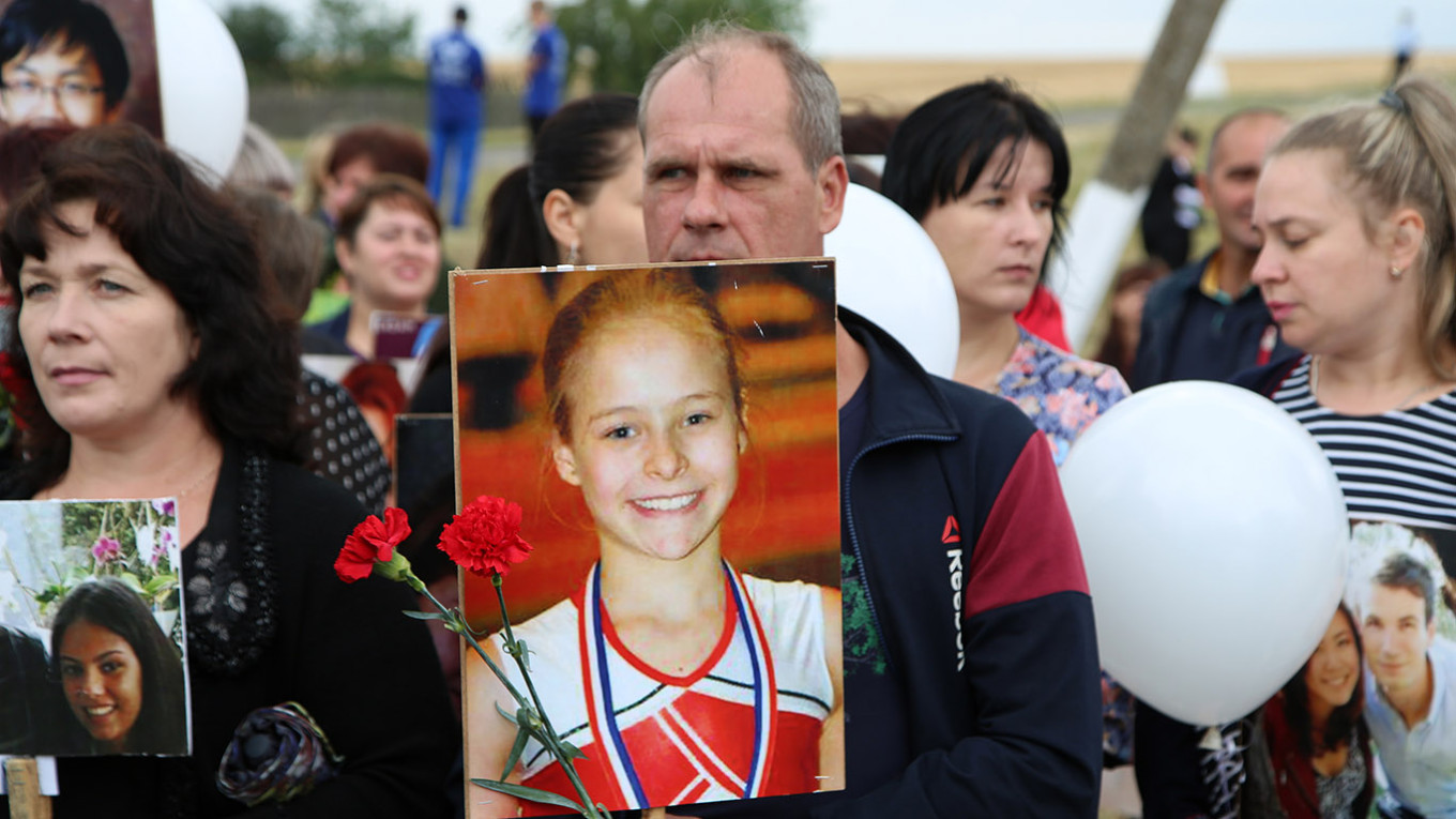People hold portraits of victims at an event to mark the sixth anniversary of the downing of Malaysia Airlines Flight MH17. Valentin Sprinchak / TASS